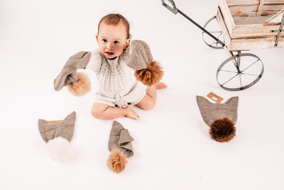 Child's alpaca bonnet hat topped with a fluffy alpaca pom-pom, in undyed fawn and brown alpaca