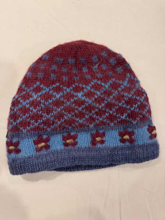 Burgundy Blooms alpaca beanie with a blue Fair Isle diamond pattern and hand-embroidered burgundy flowers with yellow centres on a pale blue band