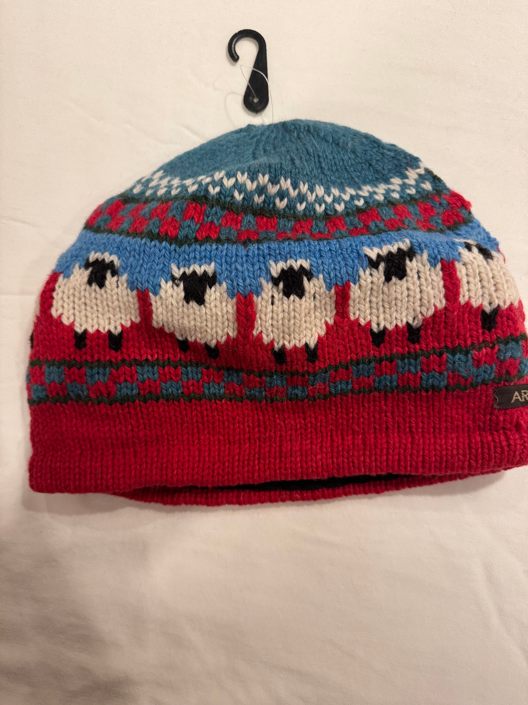 Beanie with knitted sheep around the brim — 100% alpaca, fleece-lined, teal crown with a red cuff