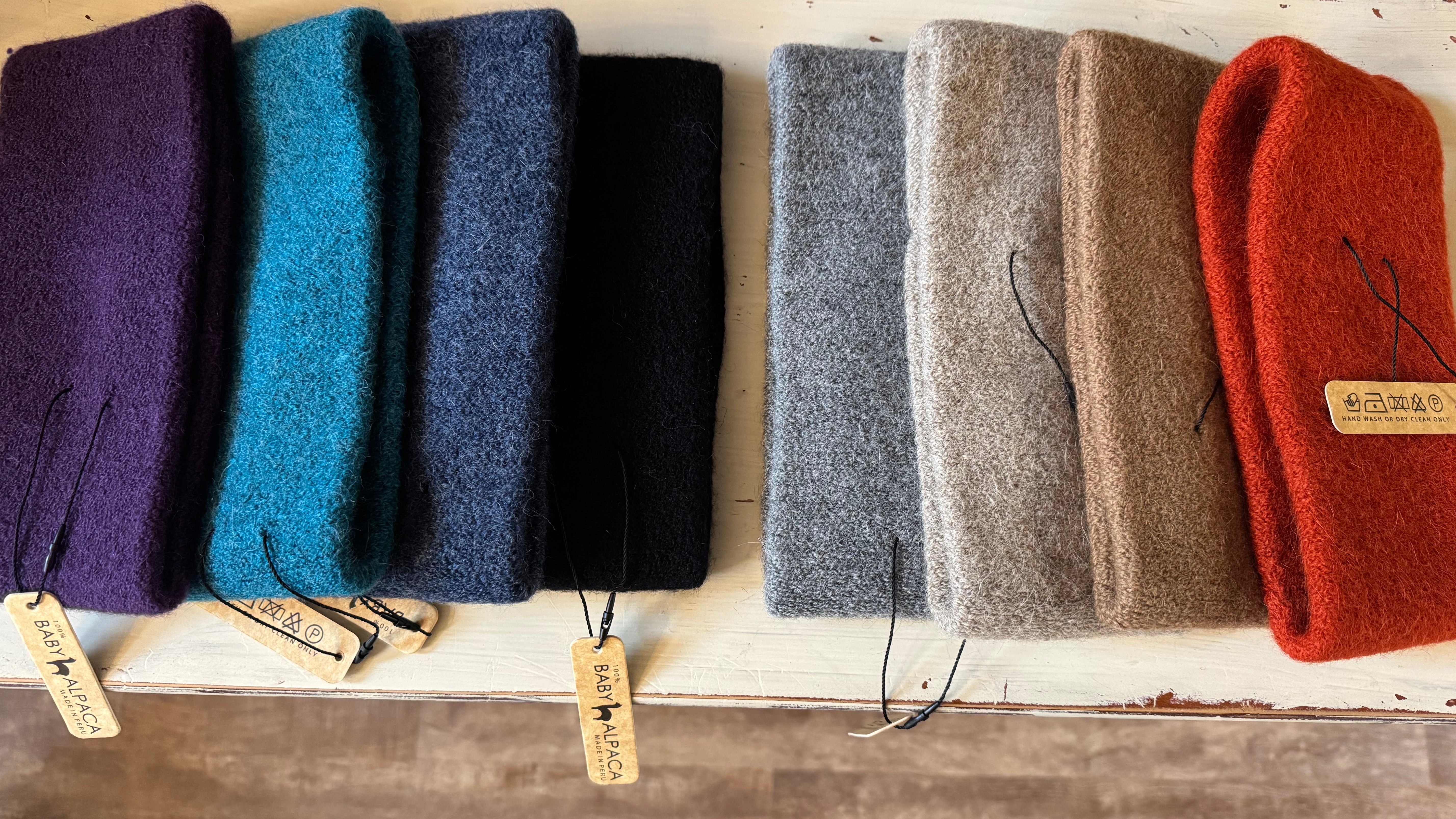 Row of colorful folded cloths on a wooden surface with tags.