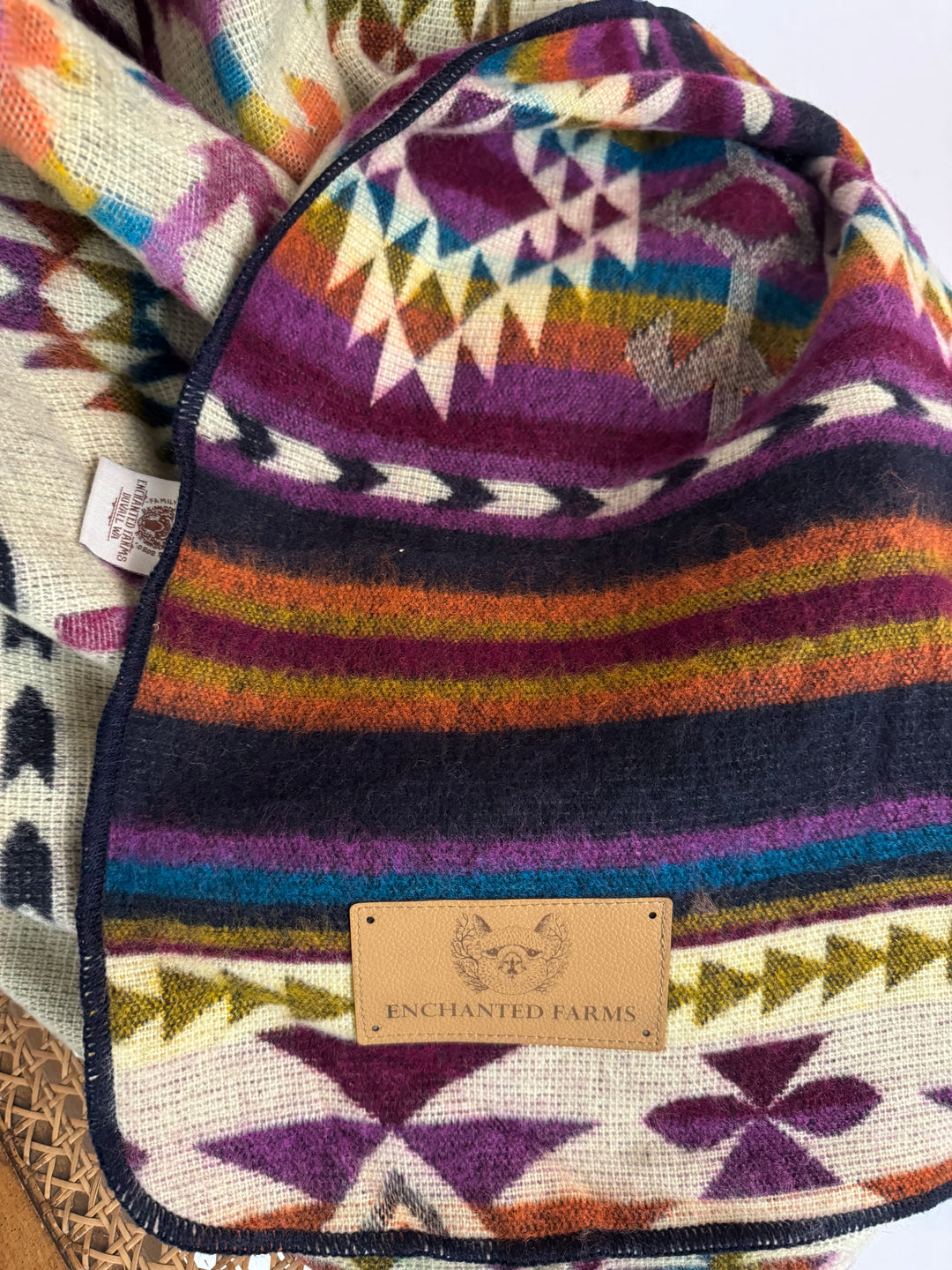 Colorful patterned fabric with alpaca wool brand label on a textured geometric pink background